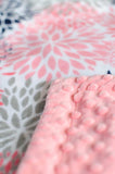 Zoomed in picture of coral, navy, and grey bloom print and coral dimple backing to throw blanket